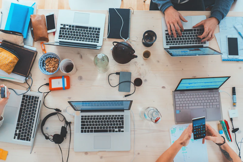 Laptops, phones and notebooks spread across a shared desk